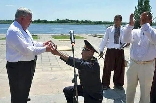 Украинский генерал стоя на коленях вручает саблю экс-послу США